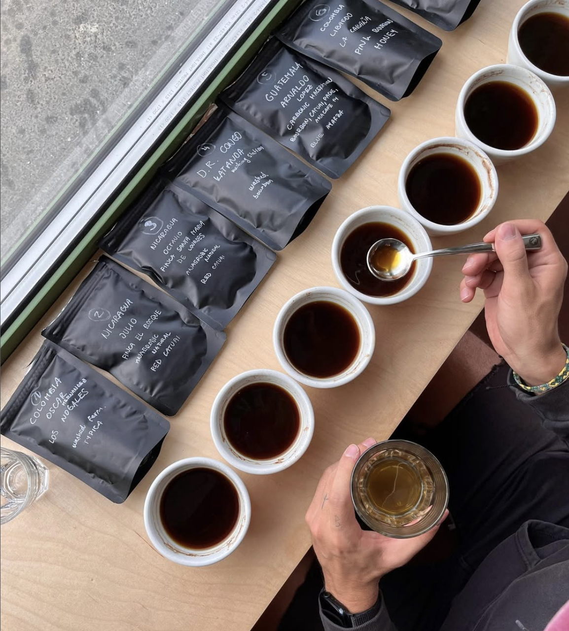 Cupping — označené balíčky kávy a šálky připravené k ochutnávce